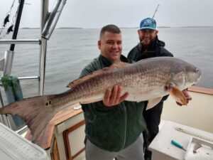 Two anglers on Pipe Dream Charters boat holding a large Redfish caught at the Amelia Island Jetties, Fernandina Beach, Florida.