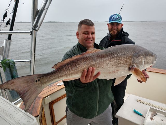 Two anglers on Pipe Dream Charters boat holding a large Redfish caught at the Amelia Island Jetties, Fernandina Beach, Florida.