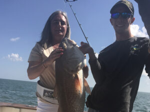 Anglers holding a large bull Redfish caught on an Amelia Island offshore fishing charter with Pipe Dream Charters.
