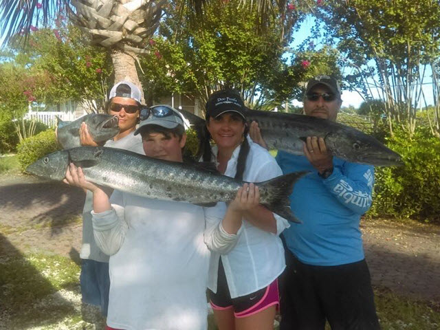 Family holding freshly caught King Mackerel during a fishing charter in Amelia Island, Florida.