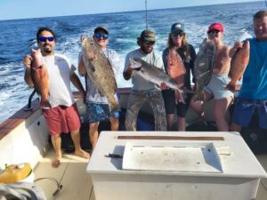 Five Anglers on back of boat showcasing their catch.