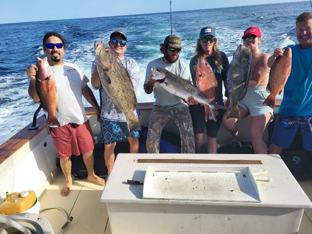 Five Anglers on back of boat showcasing their catch.