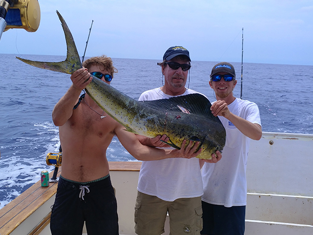 Three anglers on Pipe Dream Charters boat holding a large Mahi caught offshore near Amelia Island, Florida.
