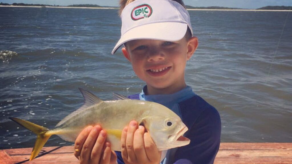 A kid holding a fish on the deck of Pipe Dream III in Cumberland Sound off Amelia Island, Florida — a Pipe Dream Charters 4-hour private family fishing charter departing from Fernandina Harbor Marina