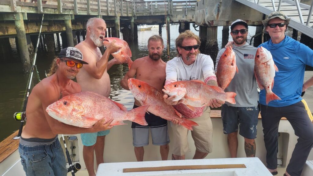 Red snapper fishing charters Amelia Island: Anglers holding American red snappers on the deck of Pipe Dream III at The Ledge off Amelia Island, Florida, on a Pipe Dream Charters private offshore trip from Fernandina Harbor Marina during the federal South Atlantic red snapper season
